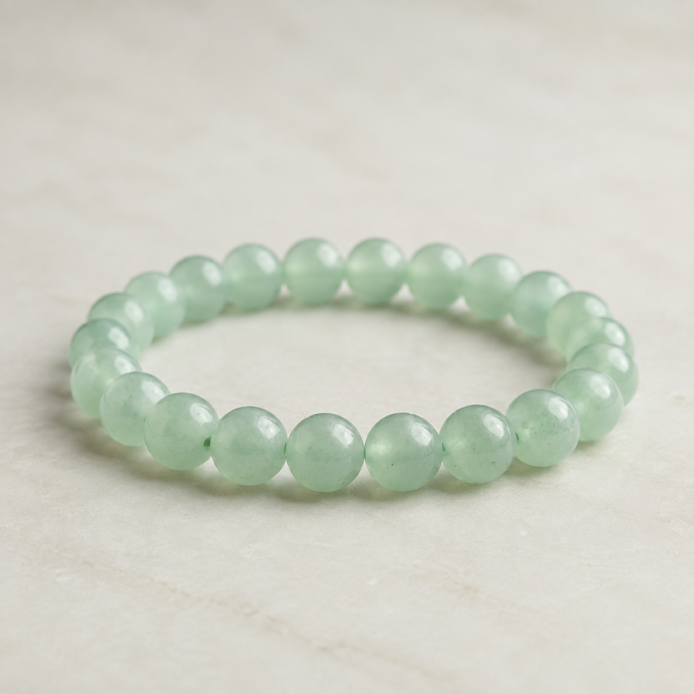Pale-green LUCK round-bead bracelet on a pearl-ivory surface