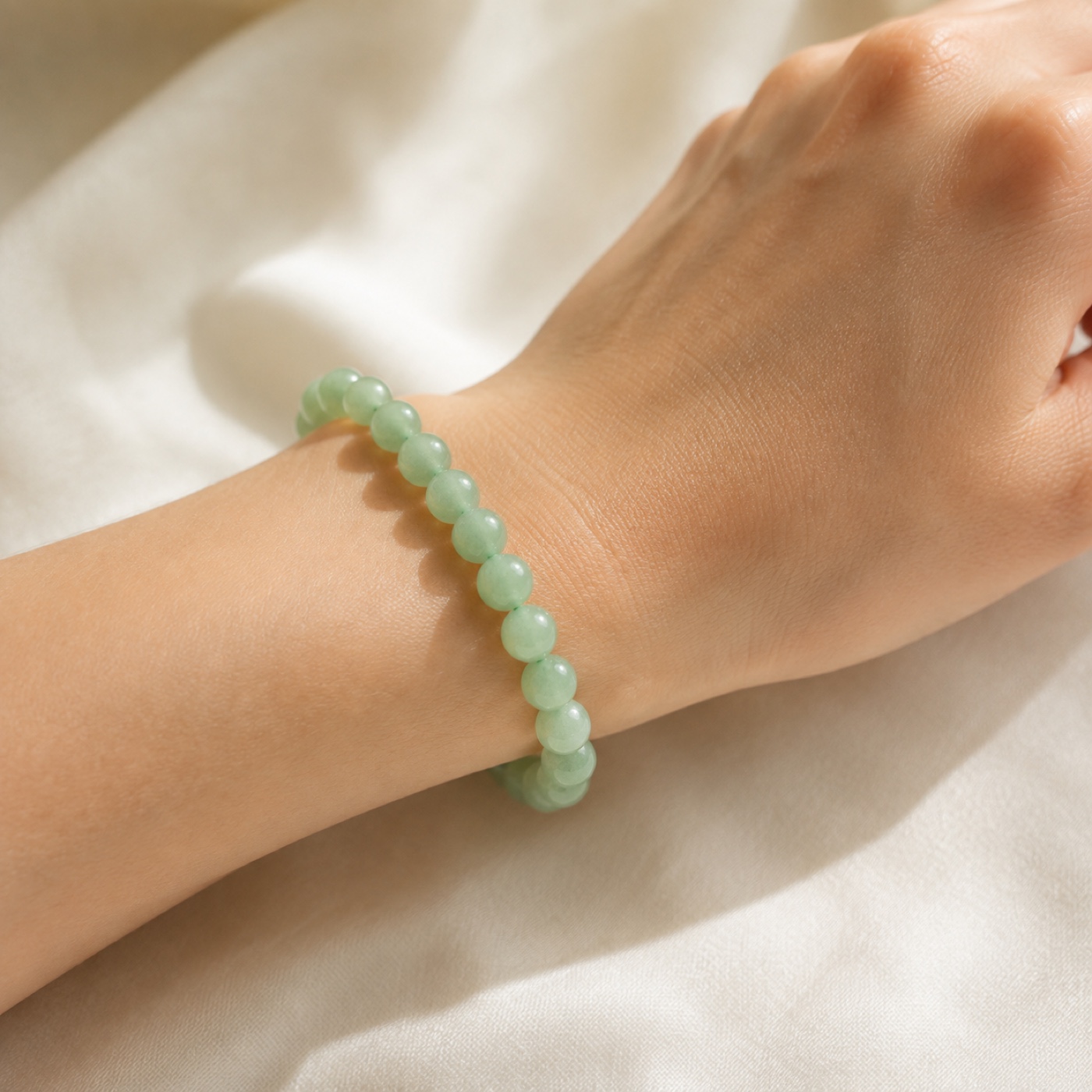 Close detail of the pale-green round beads and stretch construction